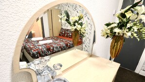 A hotel room with a bed, a mirror, a vase with flowers, a tray with toiletries, and a small table. - Blackpool Central Hotel (Blackpool)
