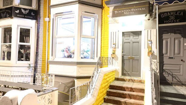 A hotel entrance with a checkered floor, a staircase with yellow steps, and a window with flowers. - Blackpool Central Hotel (Blackpool)