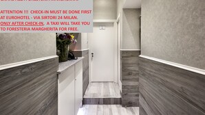 A hotel reception area with a modern design, featuring a reception desk, a vase with flowers, and a door leading to another room. - Foresteria Margherita Milano (Milan)