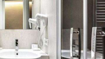 A modern bathroom with a white sink, a glass shower enclosure, and a towel rack.