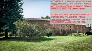 A historic building with arched windows and a brick facade, surrounded by trees and grass. - Foresteria Margherita Milano (Milan)