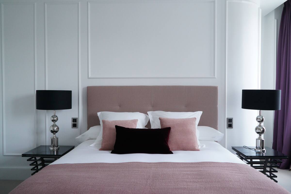 Ein ordentlich eingerichtetes Hotelzimmer mit einem großen Bett, zwei Nachttischen und einer Kopfteil.