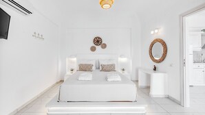 A modern bedroom with a large bed, bedside tables, a mirror, and a wall-mounted TV. - Dream Villa (Santorini)