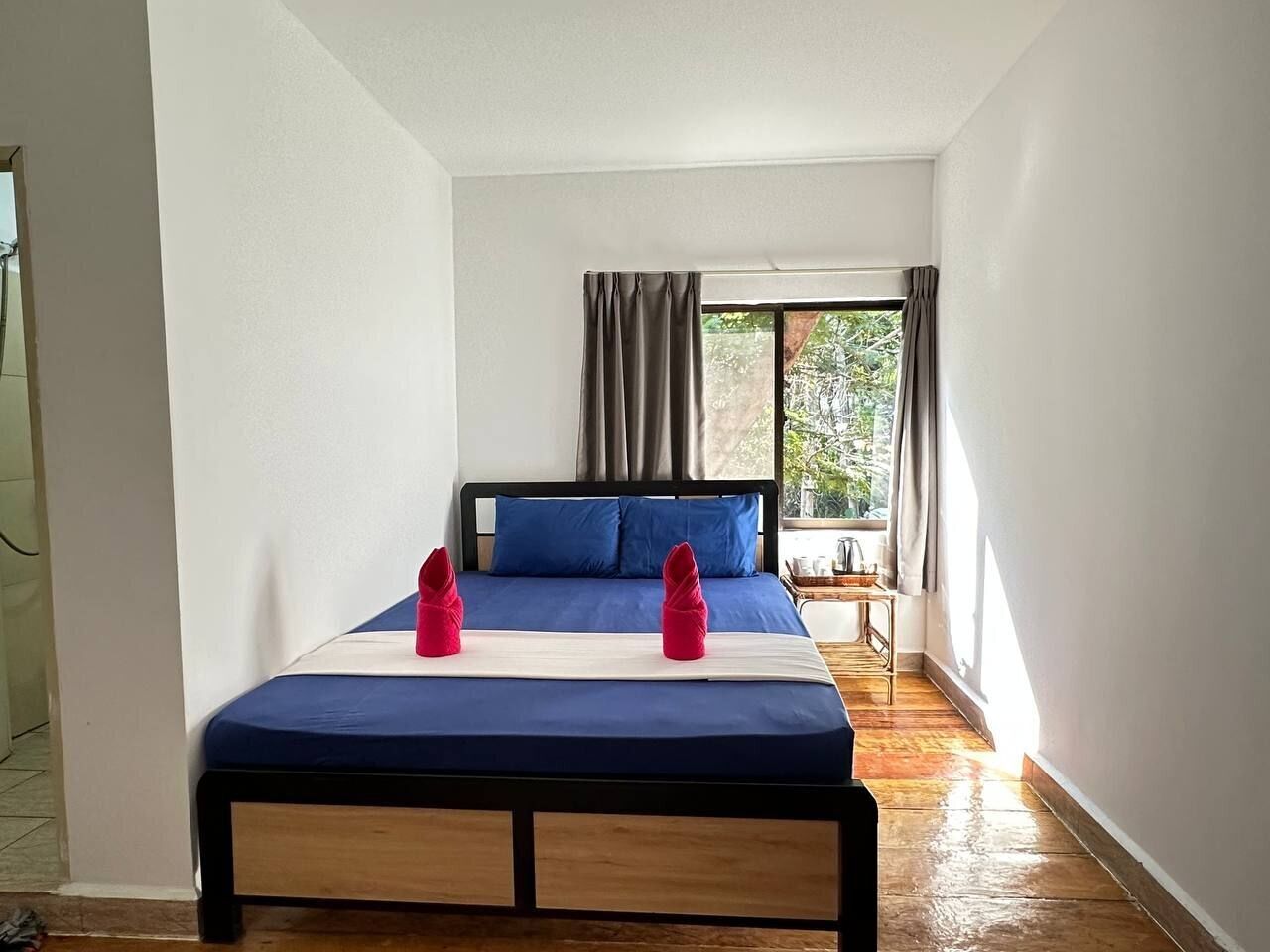 A bedroom with a bed, curtains, and a window.