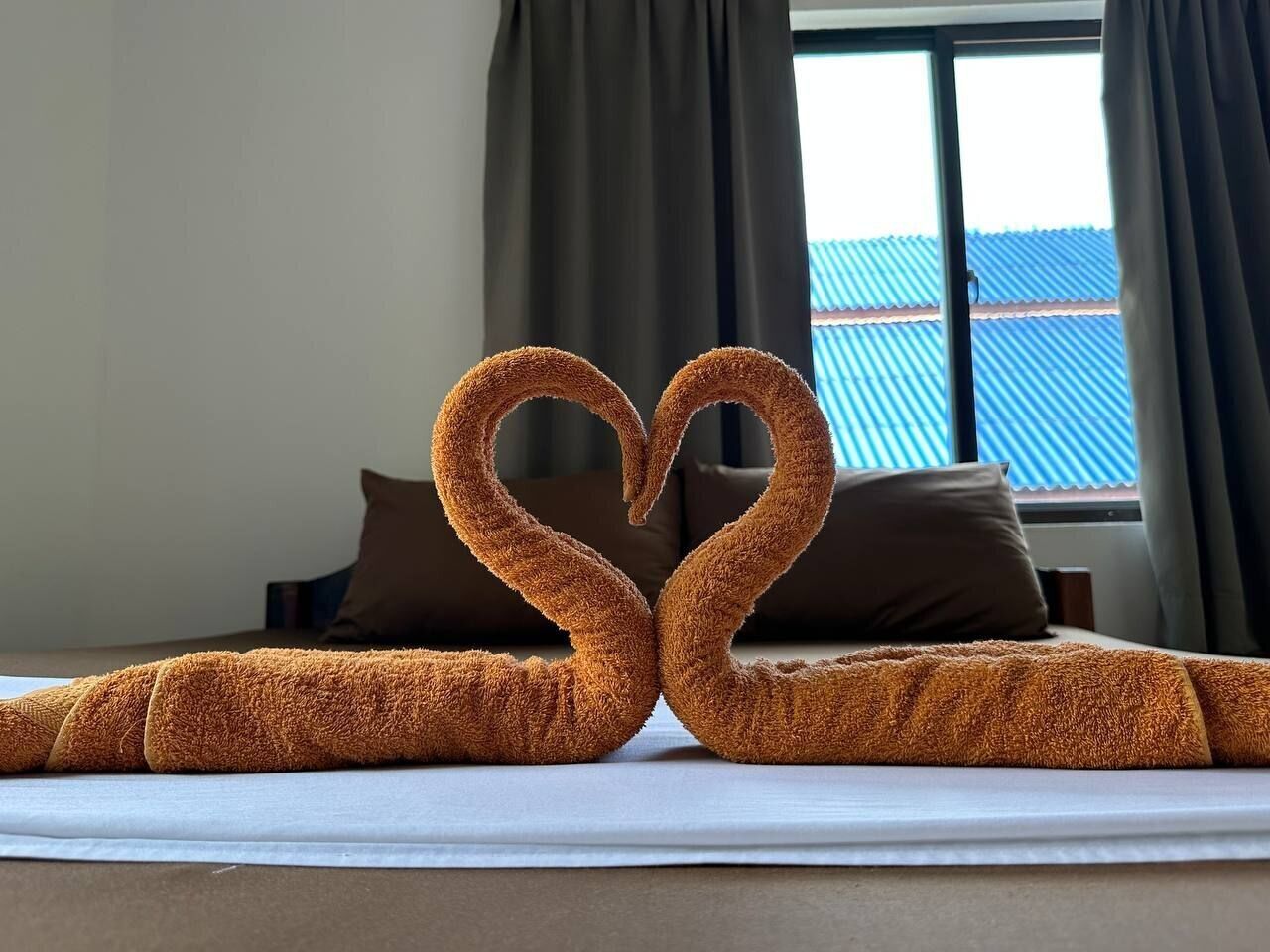 A bed with a heart-shaped arrangement of towels.