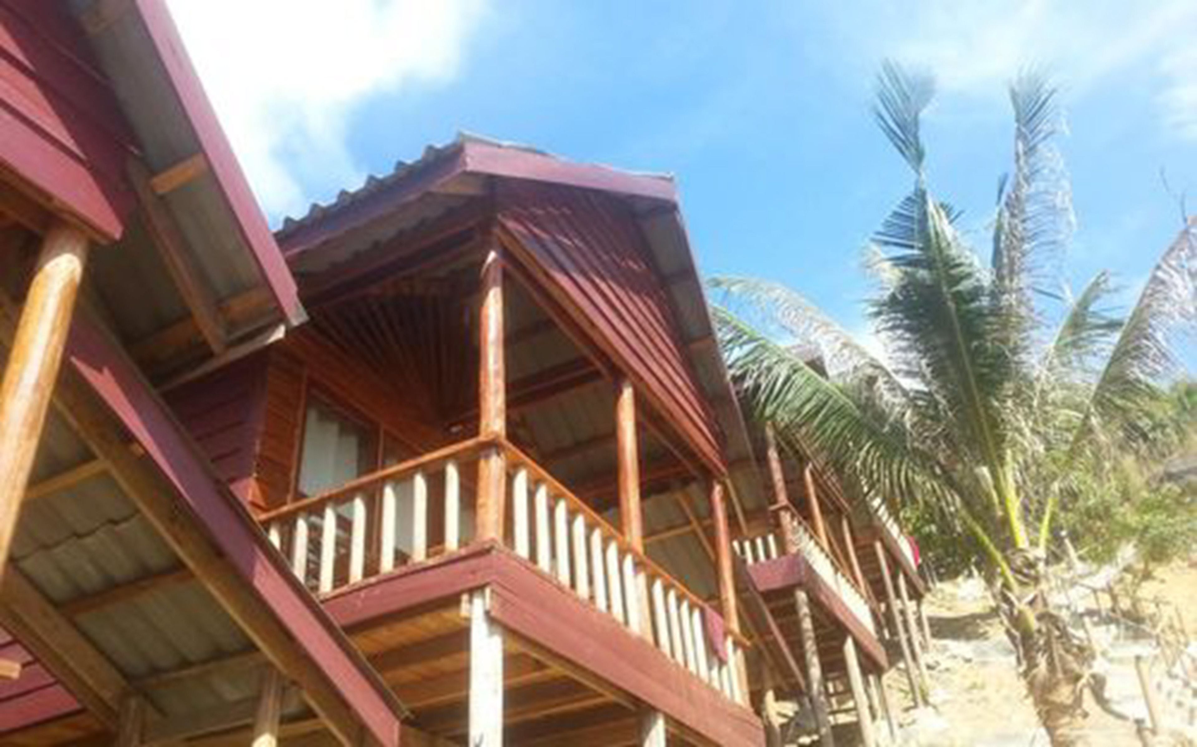 A wooden building with a balcony, surrounded by palm trees.