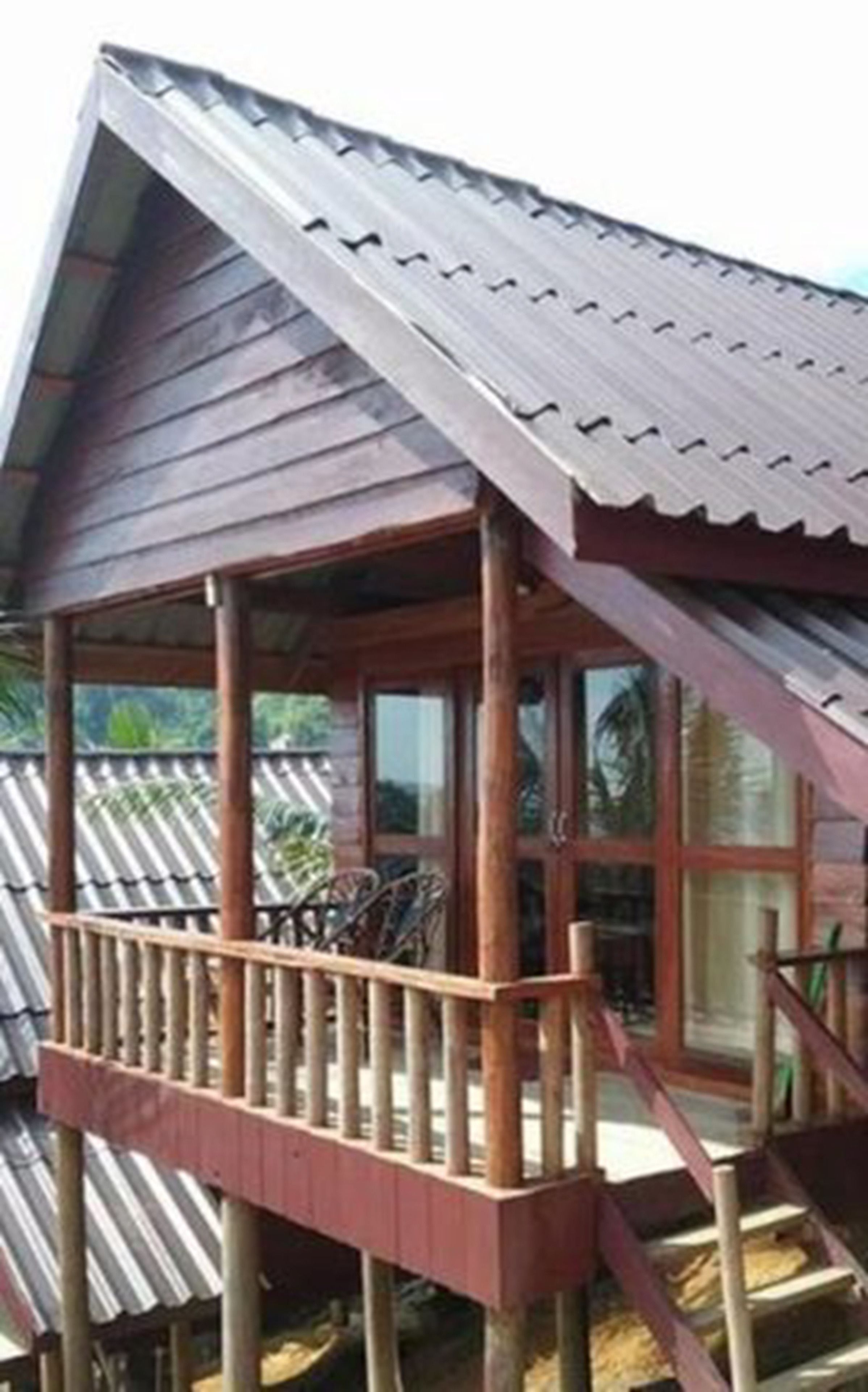 Una casa in legno con tetto in metallo, un balcone in legno e una finestra.