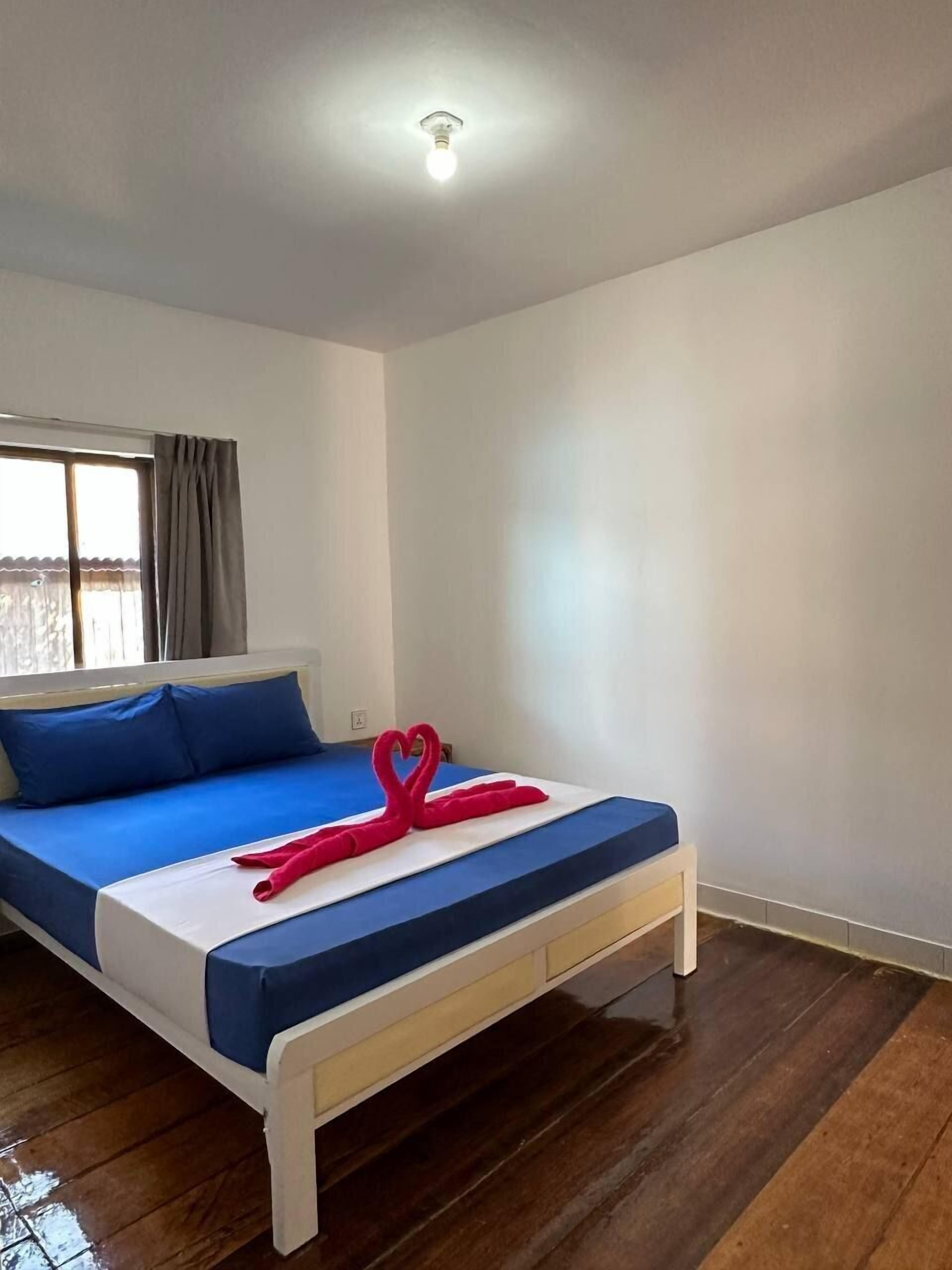 Une chambre d’hôtel avec un lit, une fenêtre avec des rideaux et un luminaire au plafond.