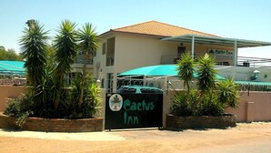 Un edifici amb un rètol que diu "Cactus Inn" i un para-sol verd.