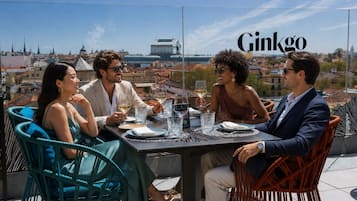 A group of people dining outdoors with a cityscape in the background.