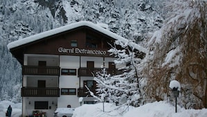 A multi-story building named "Garnier Defranceco" with a sloped roof, balconies, and a snow-covered exterior. - Albergo Garni Defrancesco (Campitello di Fassa)