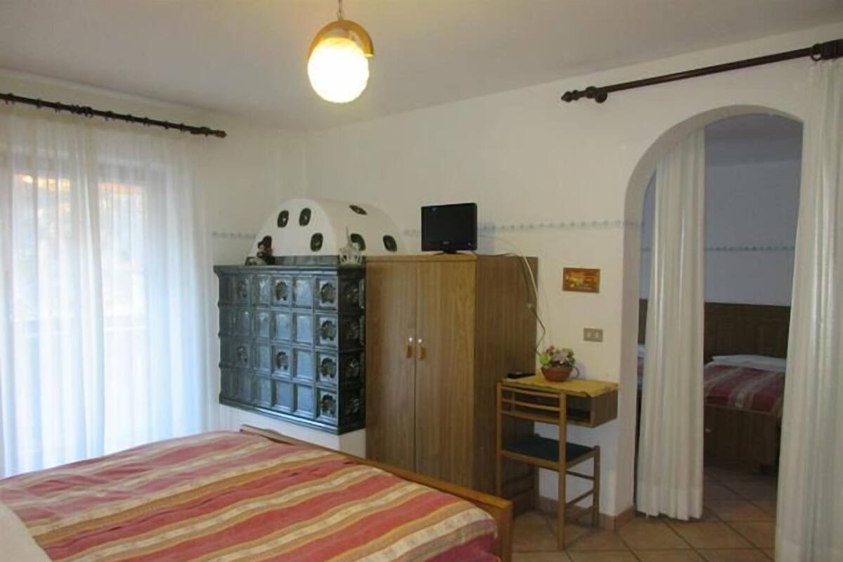 A bedroom with a bed, a wardrobe, a desk, and a television.