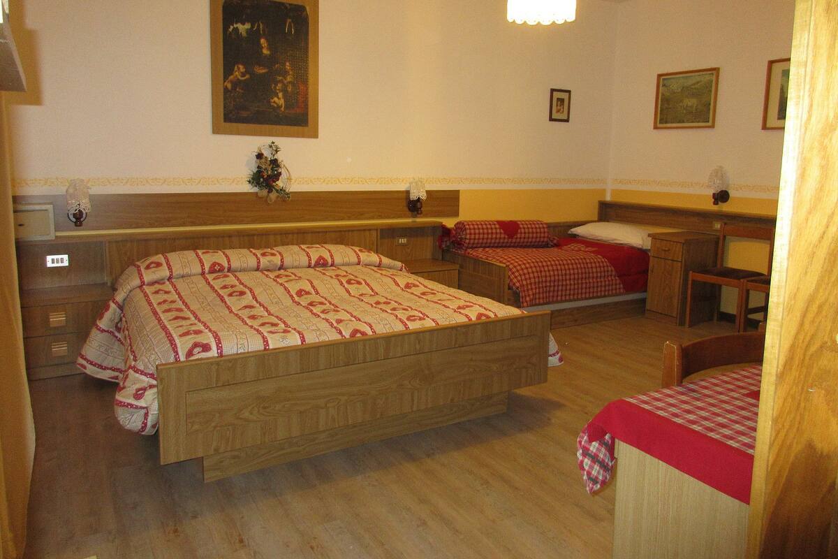 A hotel room with two wooden beds, a wooden dresser, a desk, and a chair.