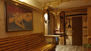 A wooden bench and a painting in a rustic room with a wooden door and a small shelf with a decorative item. - Albergo Garni Defrancesco (Campitello di Fassa)