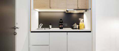 Een moderne keuken met witte kasten, een zwart aanrecht en een roestvrijstalen afzuigkap.
