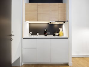 Une cuisine moderne avec des meubles blancs, un plan de travail noir et une hotte en acier inoxydable.