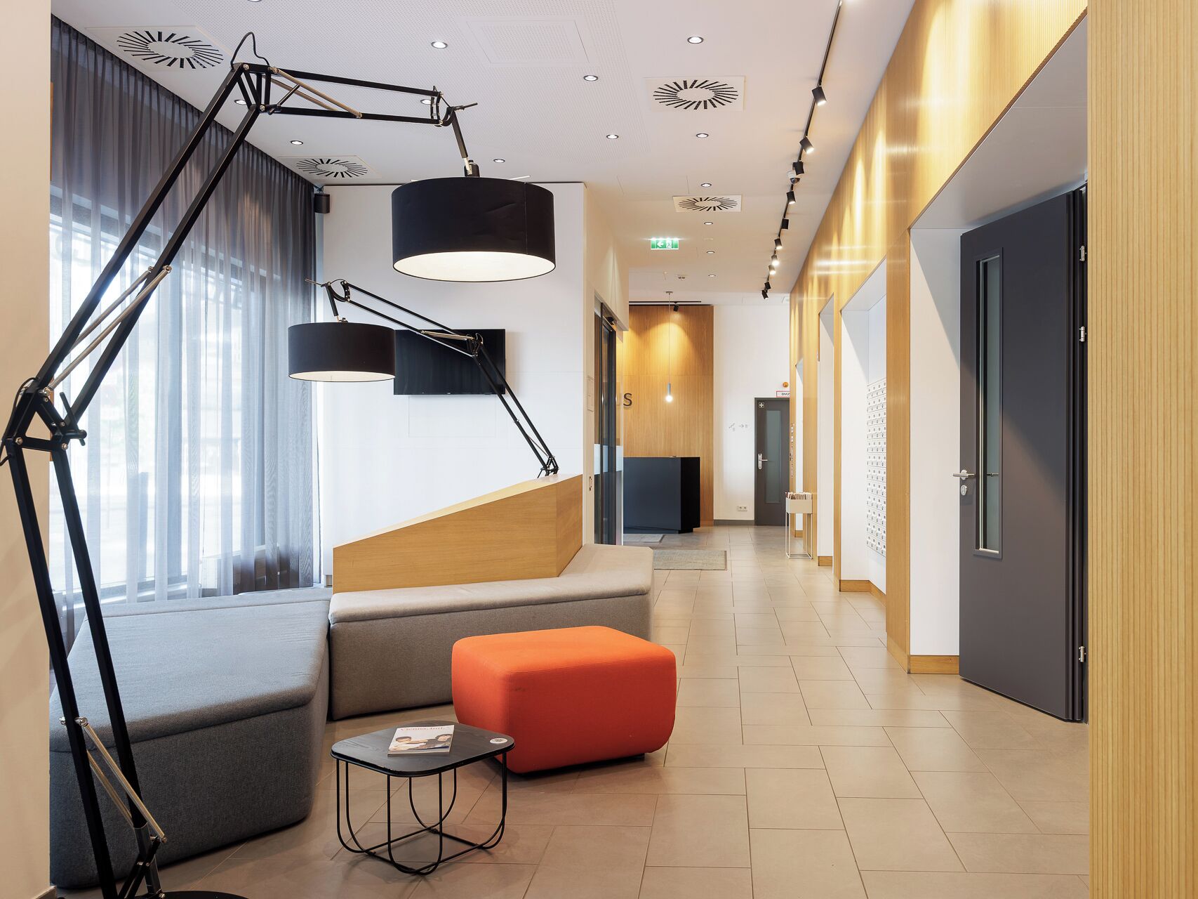 Un lobby moderno con una escalera, zona de estar y mostrador de recepción.