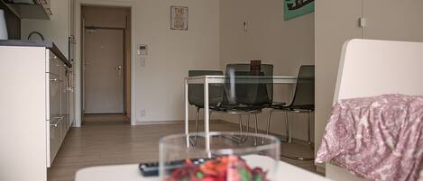 Uma sala de estar moderna com uma mesa de centro de vidro, um sofá branco e uma área de jantar com mesa e cadeiras.