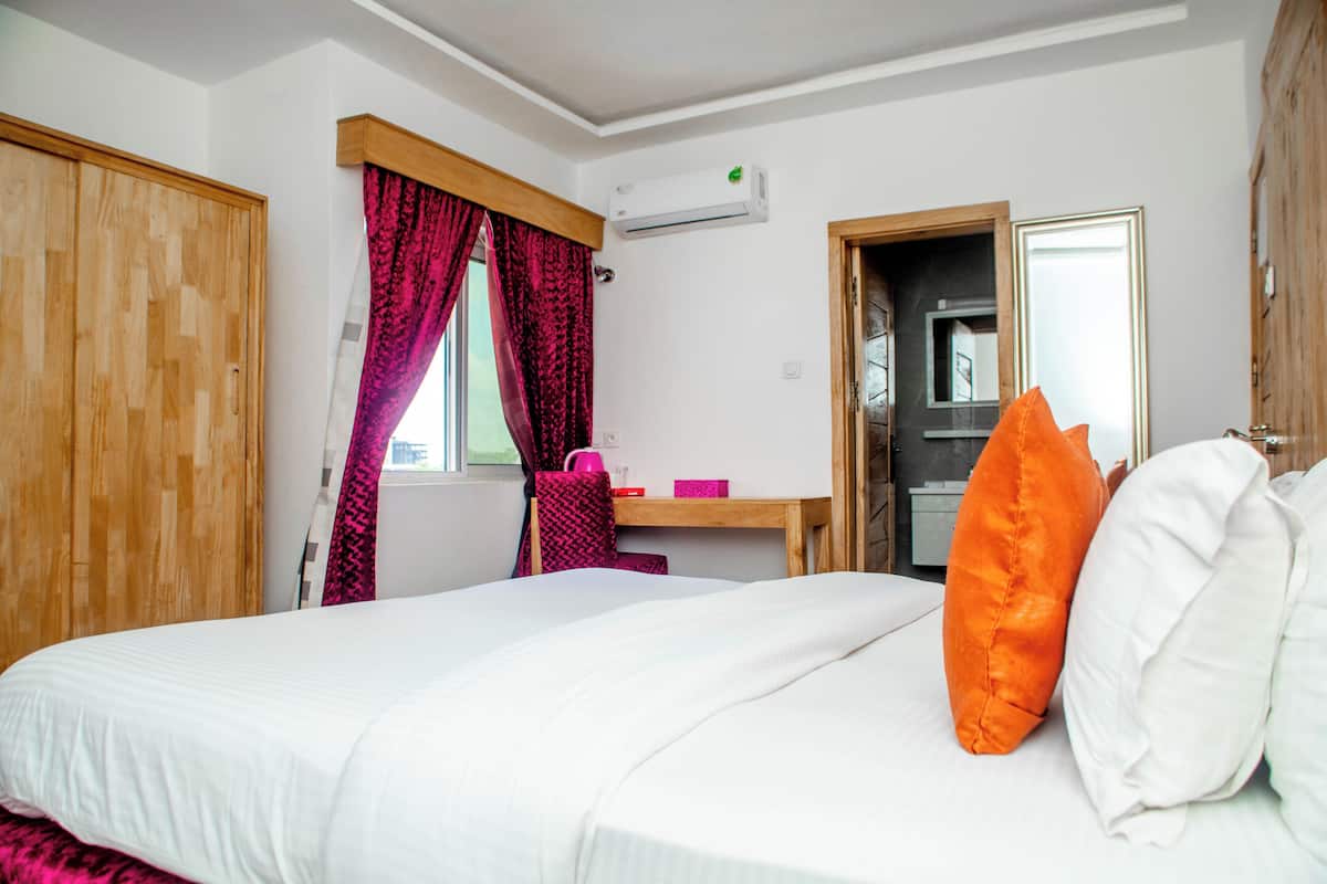 Une chambre à coucher comprenant un lit, un bureau, un climatiseur et un miroir.