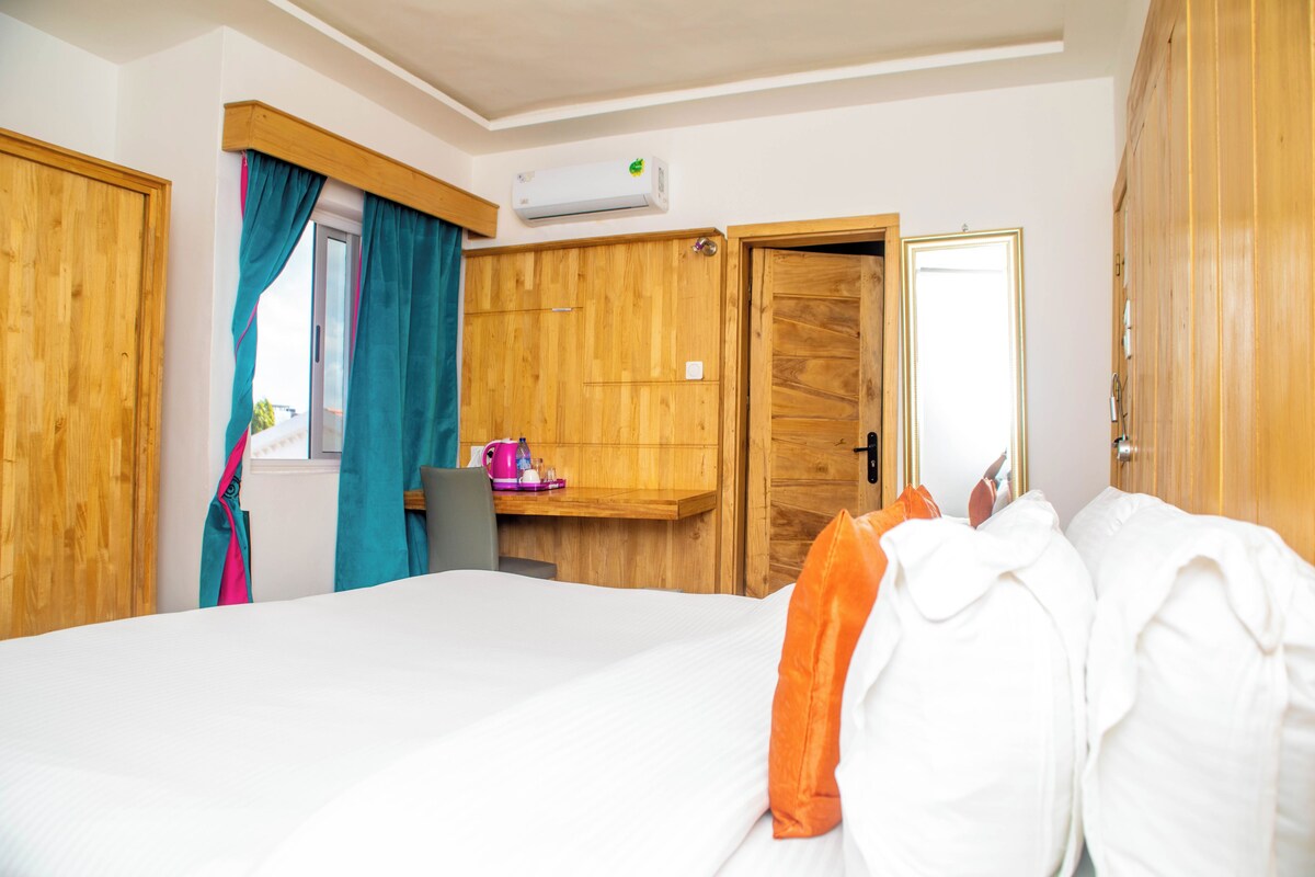 Un dormitorio con una cama, un armario de madera, un escritorio con una silla y un equipo de aire acondicionado.