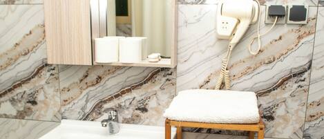 A bathroom with a marble backsplash, a wooden vanity with a sink, a mirror, and a towel rack.