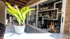 Zona de bar con una planta en maceta grande, encimera de mármol y estanterías llenas de botellas de licor.