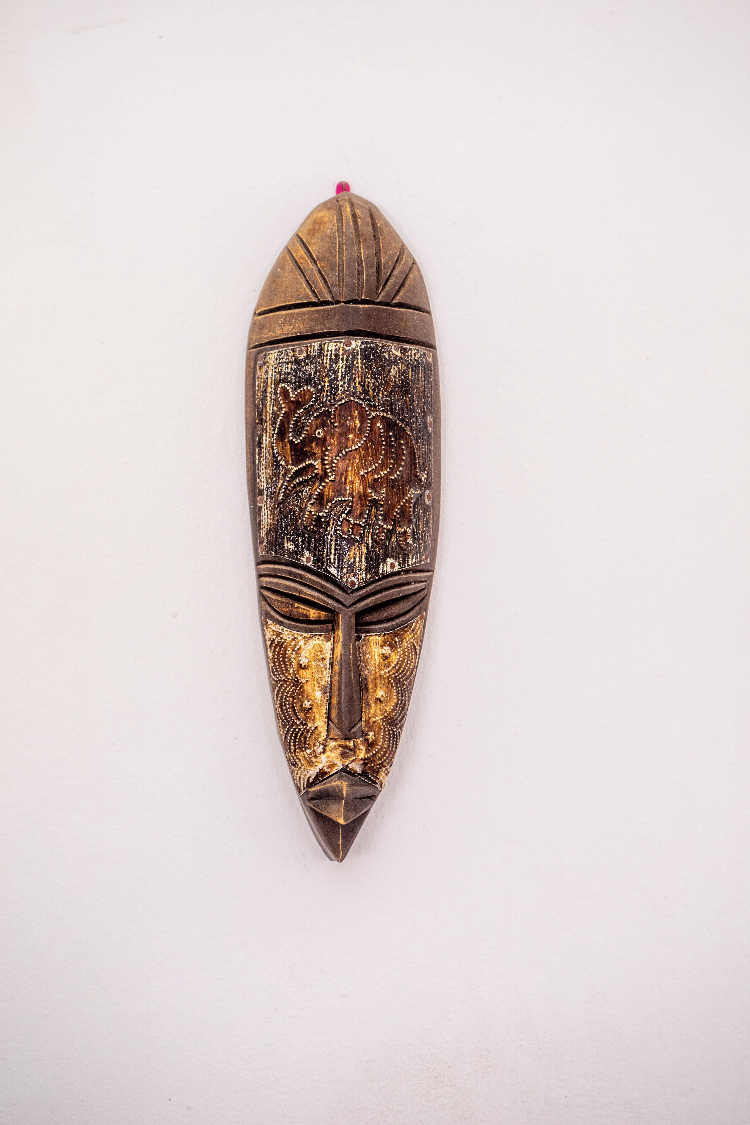 A wooden mask with intricate carvings and a pointed top.