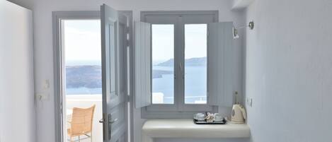 A bathroom with a view of the sea, a toilet, a sink, and a chair.