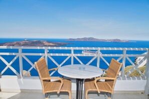 Un balcon agrémenté de fauteuils en osier et d’une table ronde, offrant une vue imprenable sur la côte, avec ses eaux d’un bleu limpide et les îles qui se dessinent à l’horizon.