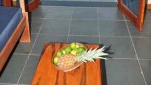 A room with a view of the beach, a wooden table with fruit, and a bed with blue curtains. - Sirius Canoa Residencial (Aracati)