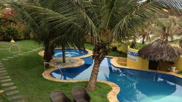 A swimming pool with a palm tree and lounge chairs.