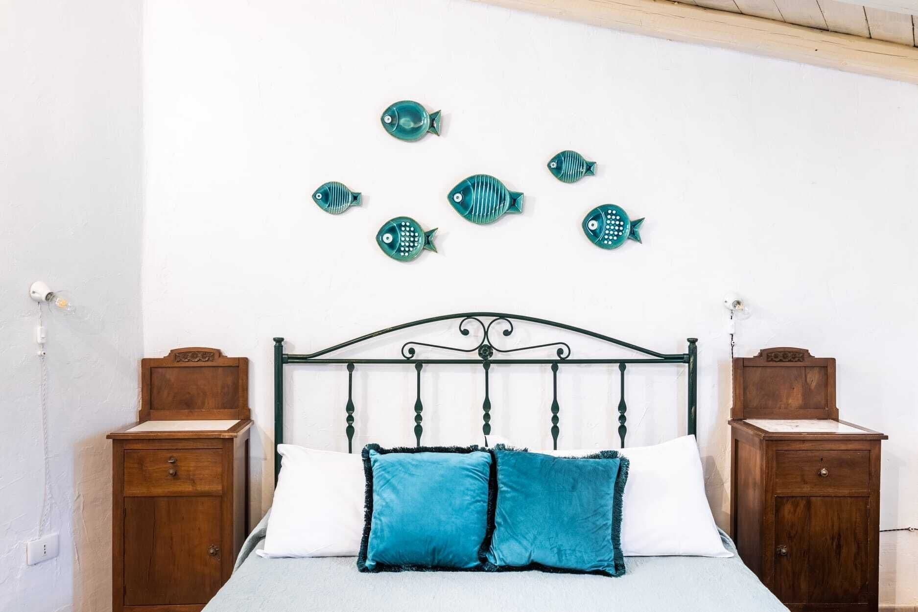 A bedroom with a bed, two nightstands, and decorative fish wall art.