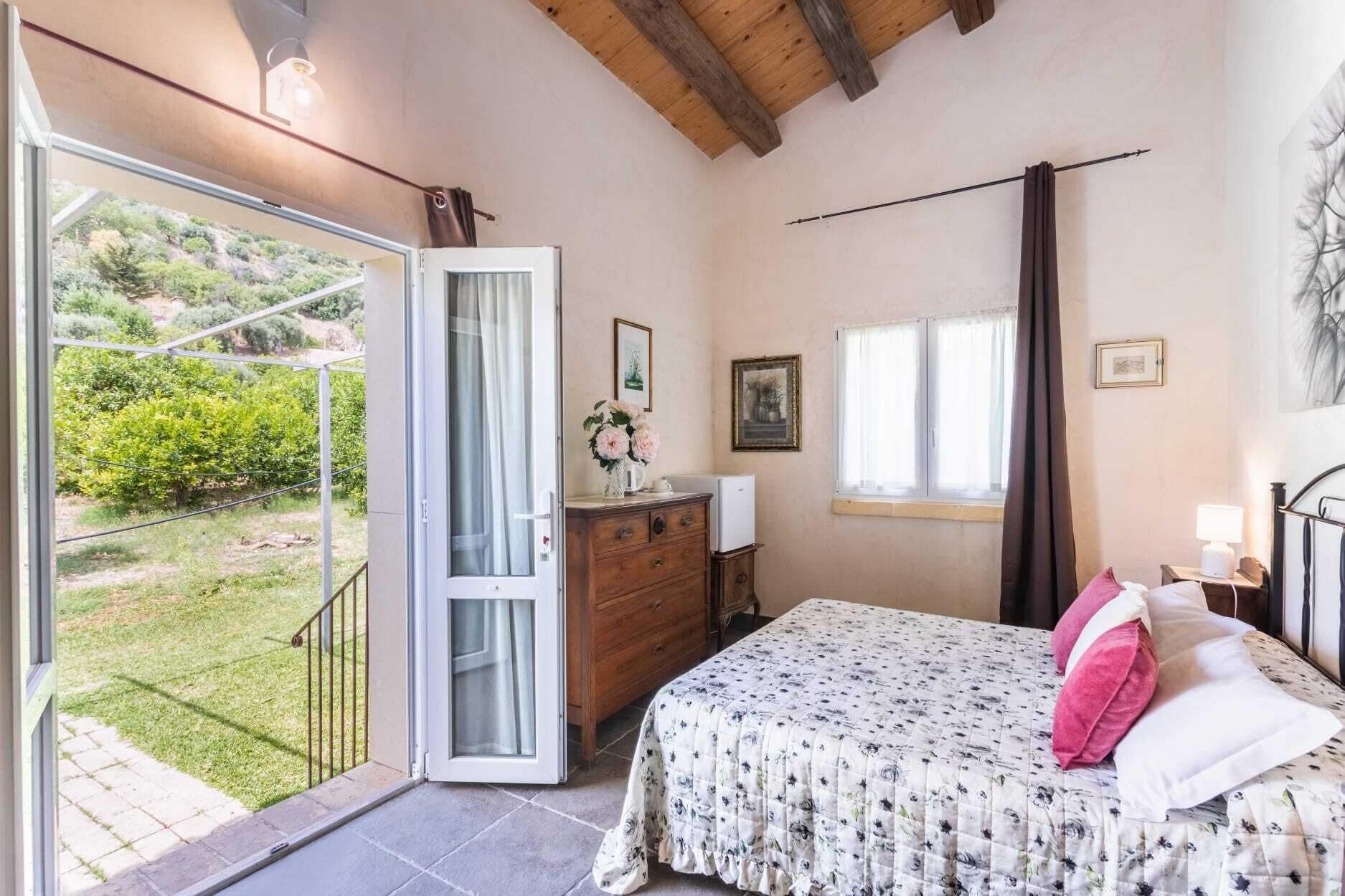 Une chambre à coucher comprenant un lit, une commode, une fenêtre et une porte donnant sur un balcon.