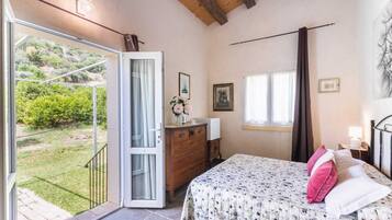 Une chambre à coucher comprenant un lit, une commode, une fenêtre et une porte donnant sur un balcon.