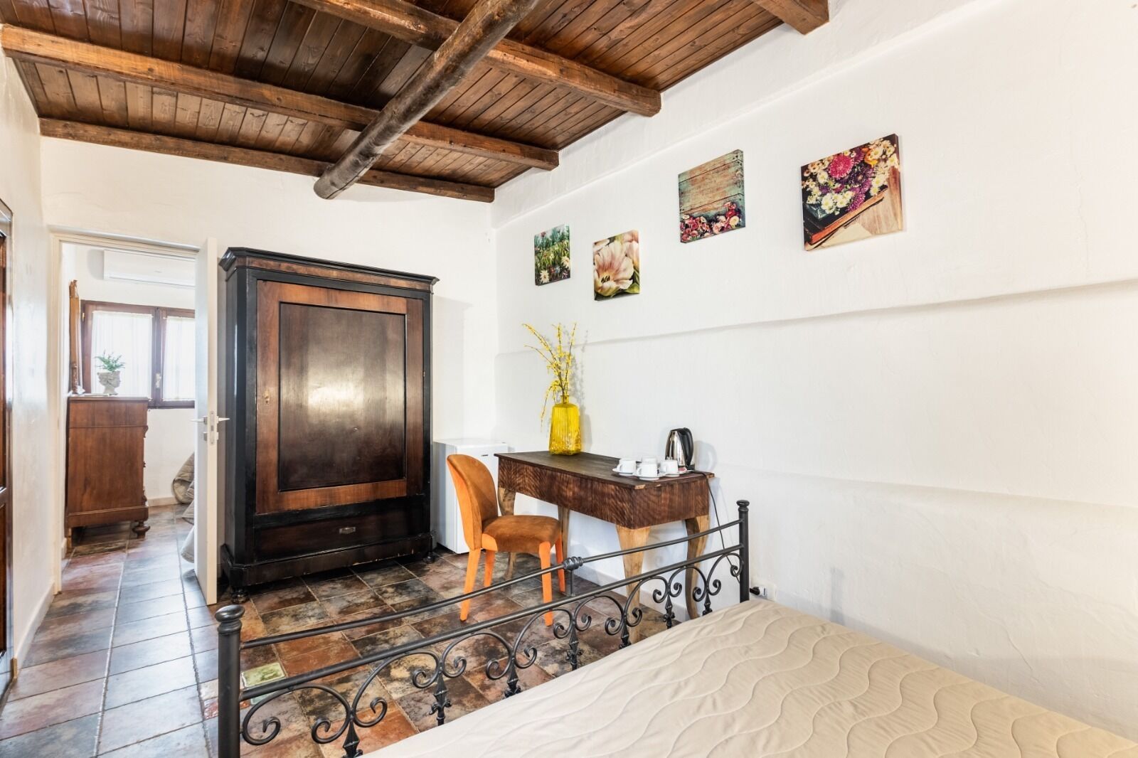 A room with a wooden door, a desk with a chair, a bed, and a staircase.