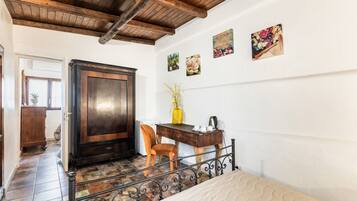 Una habitación con puerta de madera, un escritorio con silla, una cama y una escalera.