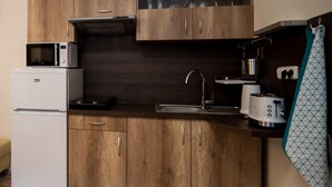 Une cuisine compacte avec des meubles de rangement en bois, un four à micro-ondes encastré, un grille-pain et un évier.