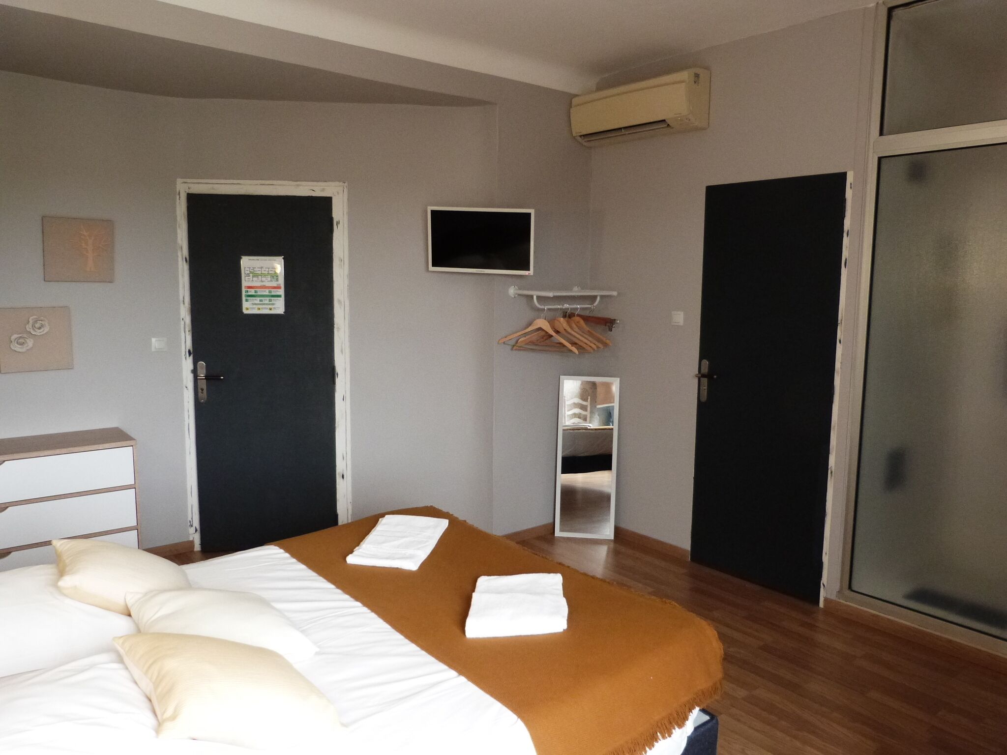 Una habitación de hotel con cama, televisión, armario y puerta.