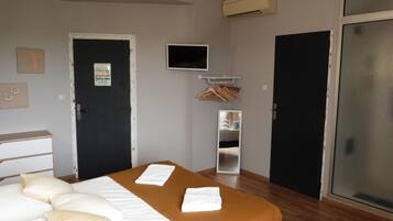 Una habitación de hotel con cama, televisión, armario y puerta.