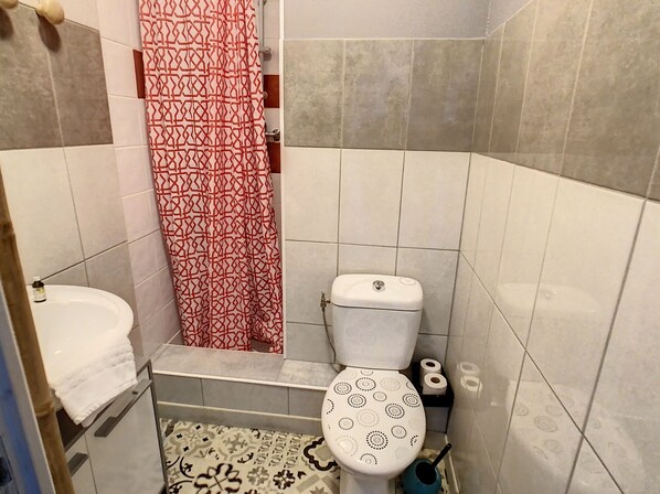 Baño con inodoro, lavamanos y cortina de ducha.