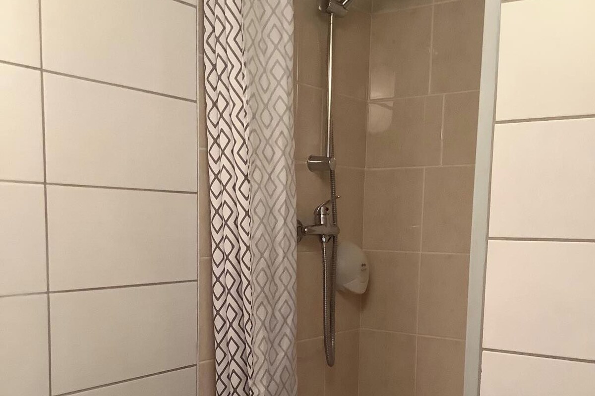 A bathroom with a shower, a sink, and a patterned shower curtain.