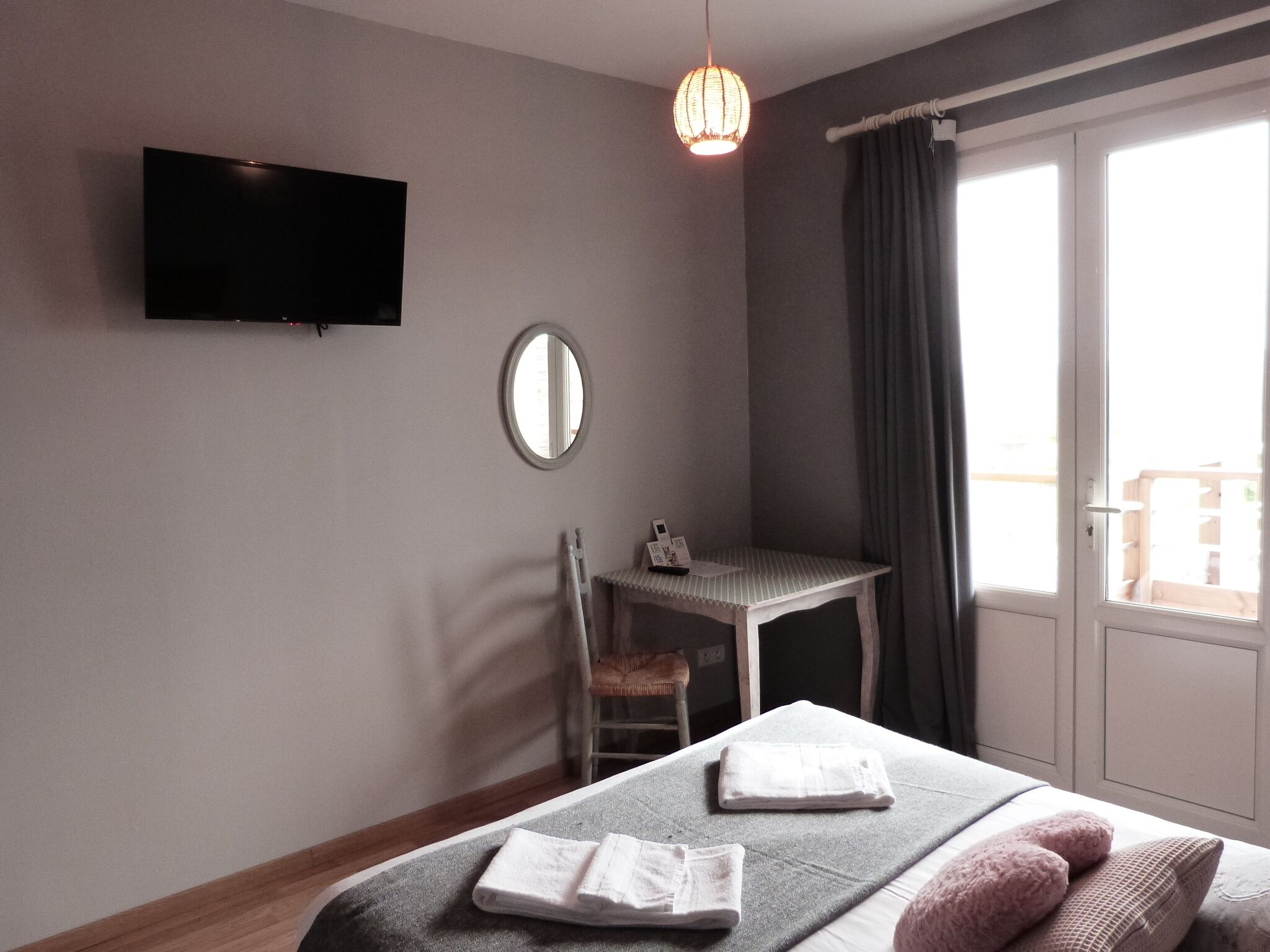 Une chambre d’hôtel équipée d’un lit, d’un bureau, d’une chaise, d’une télévision, d’un miroir et d’une fenêtre avec des rideaux.