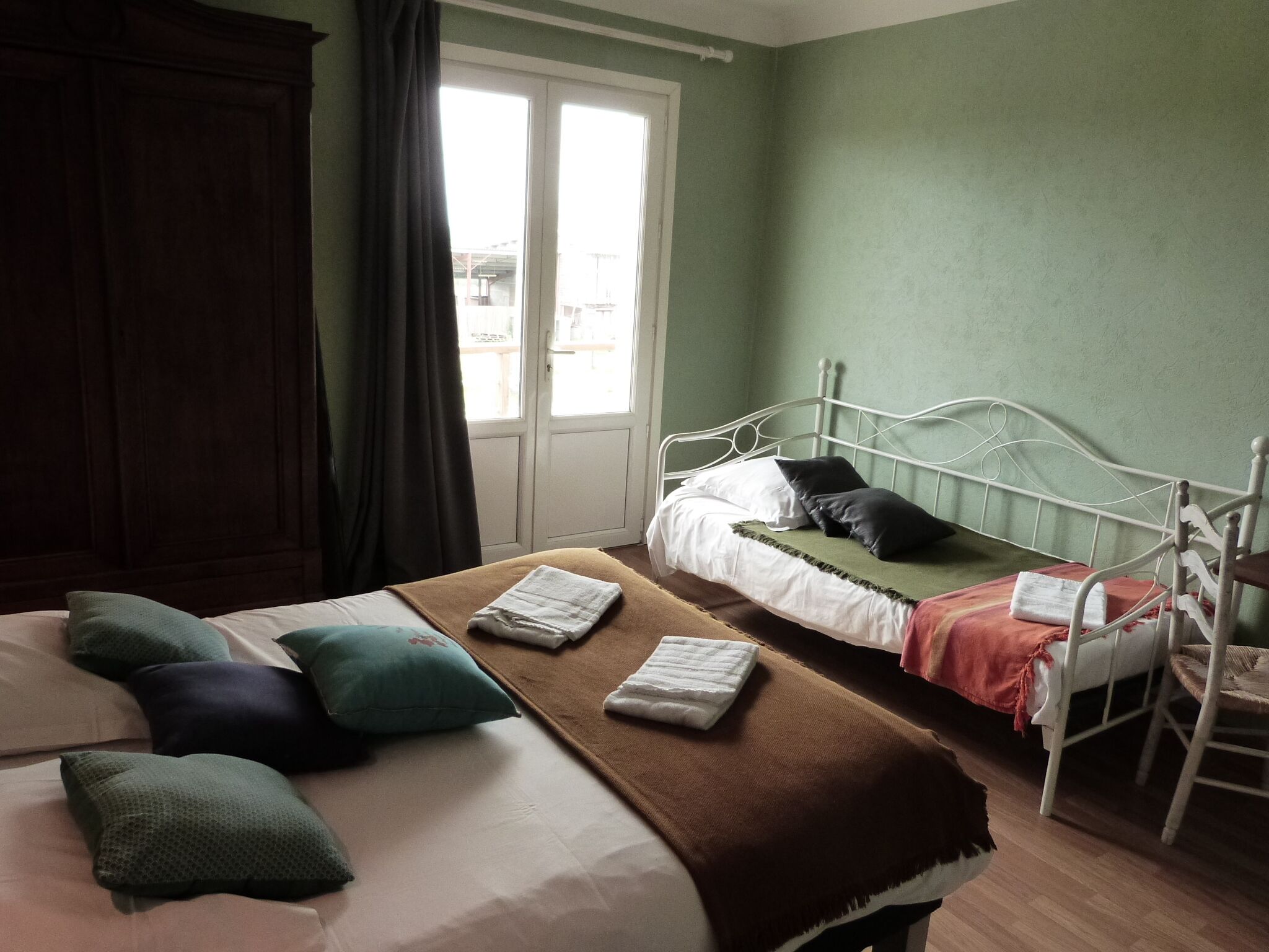 A bedroom with a bed, a chair, a window, and a door.