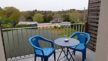 Een balkon met twee blauwe plastic stoelen en een klein rond tafeltje.