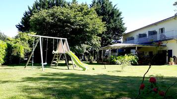 Enjoy a family-friendly backyard with a swing set, slide, and lush greenery.
