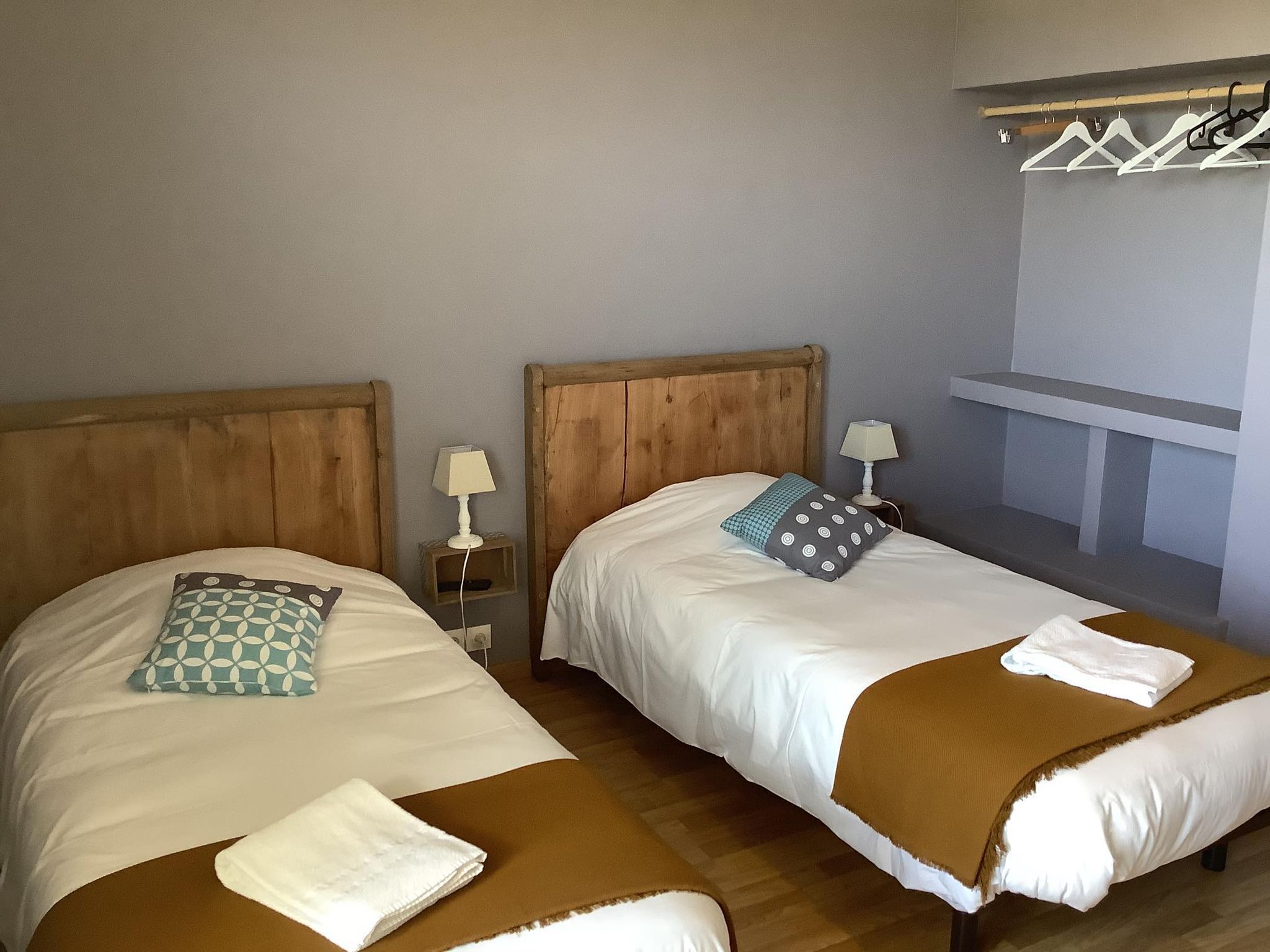 A double bed room with two wooden headboards, bedside lamps, and a small shelf.