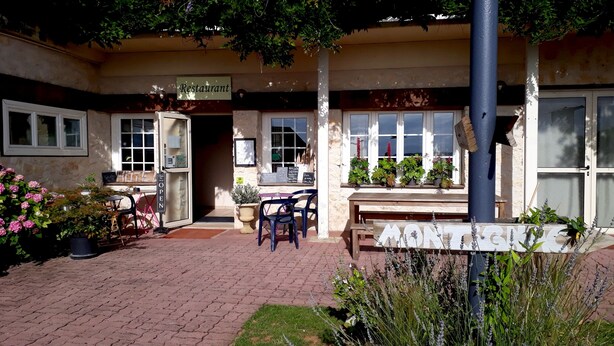 A restaurant with outdoor seating, a signboard, and potted plants. - Logis Hôtel La Borie (Saint-Genies)