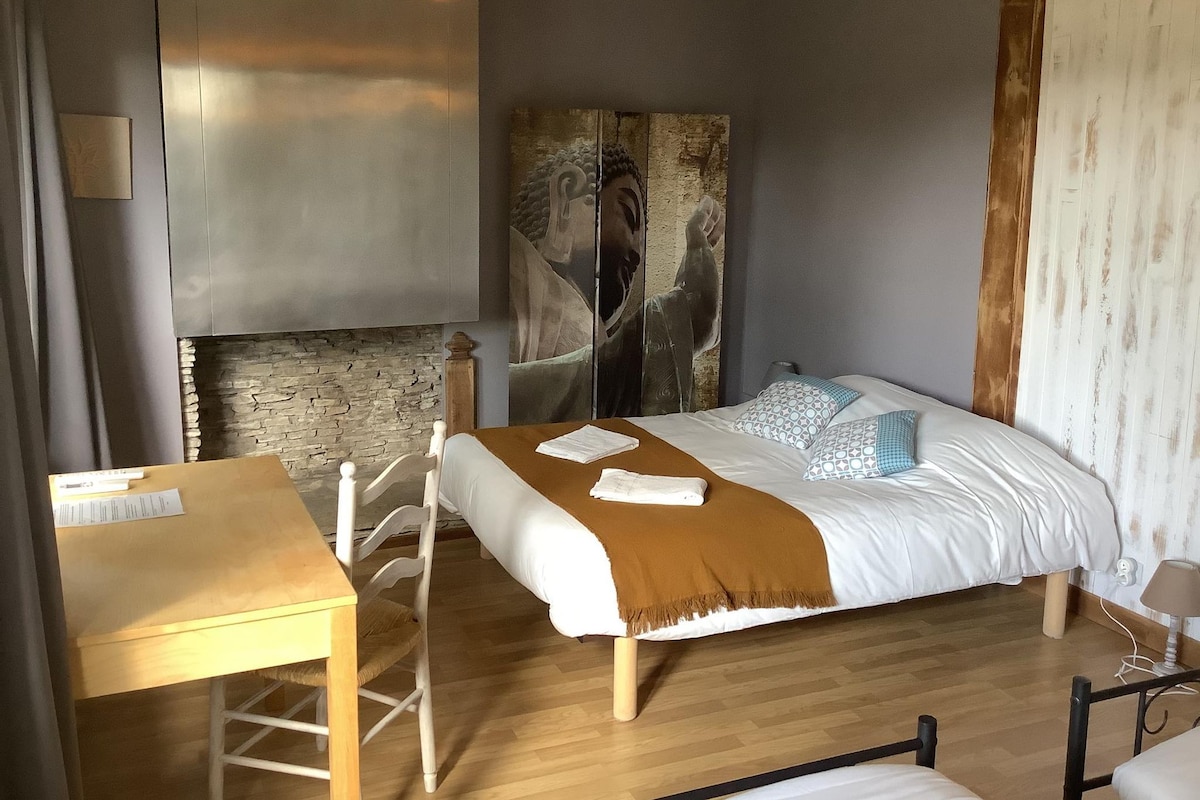 A bedroom with a bed, a desk, a lamp, and a wall-mounted artwork.