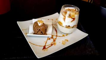 Um prato de sobremesa com uma bola de sorvete de chocolate e um copo de sobremesa em camadas com chantilly e nozes.