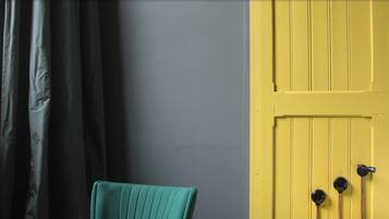 A room with a teal chair, a yellow door, and a blue patterned floor.